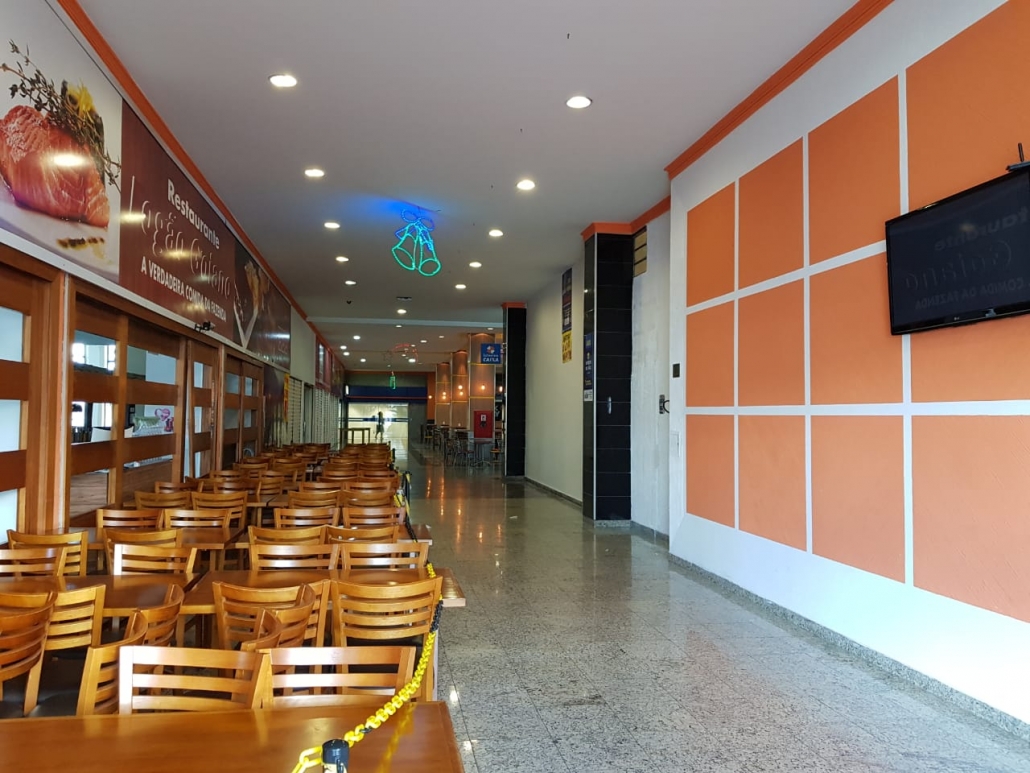 Corredor interno de circulação do SIA Centro Empresarial com piso em granito, restaurante à esquerda e painéis decorativos à direita