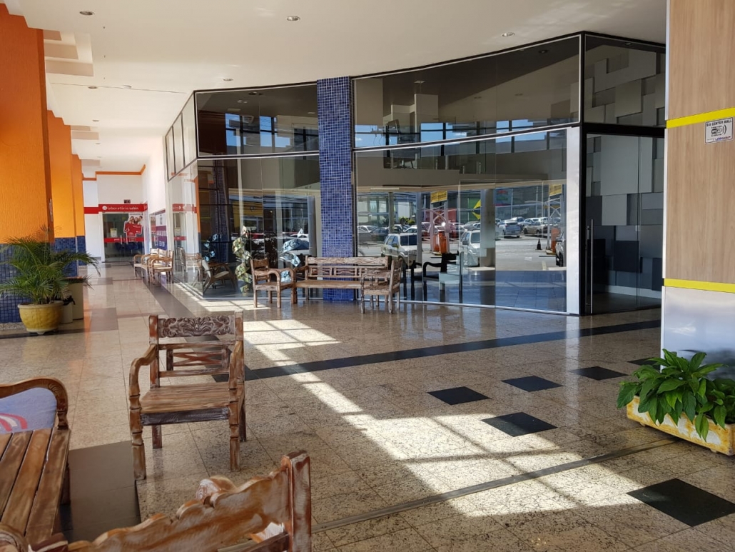 Hall de recepção do SIA Centro Empresarial com piso em granito polido, bancos de madeira e fachada envidraçada de acesso